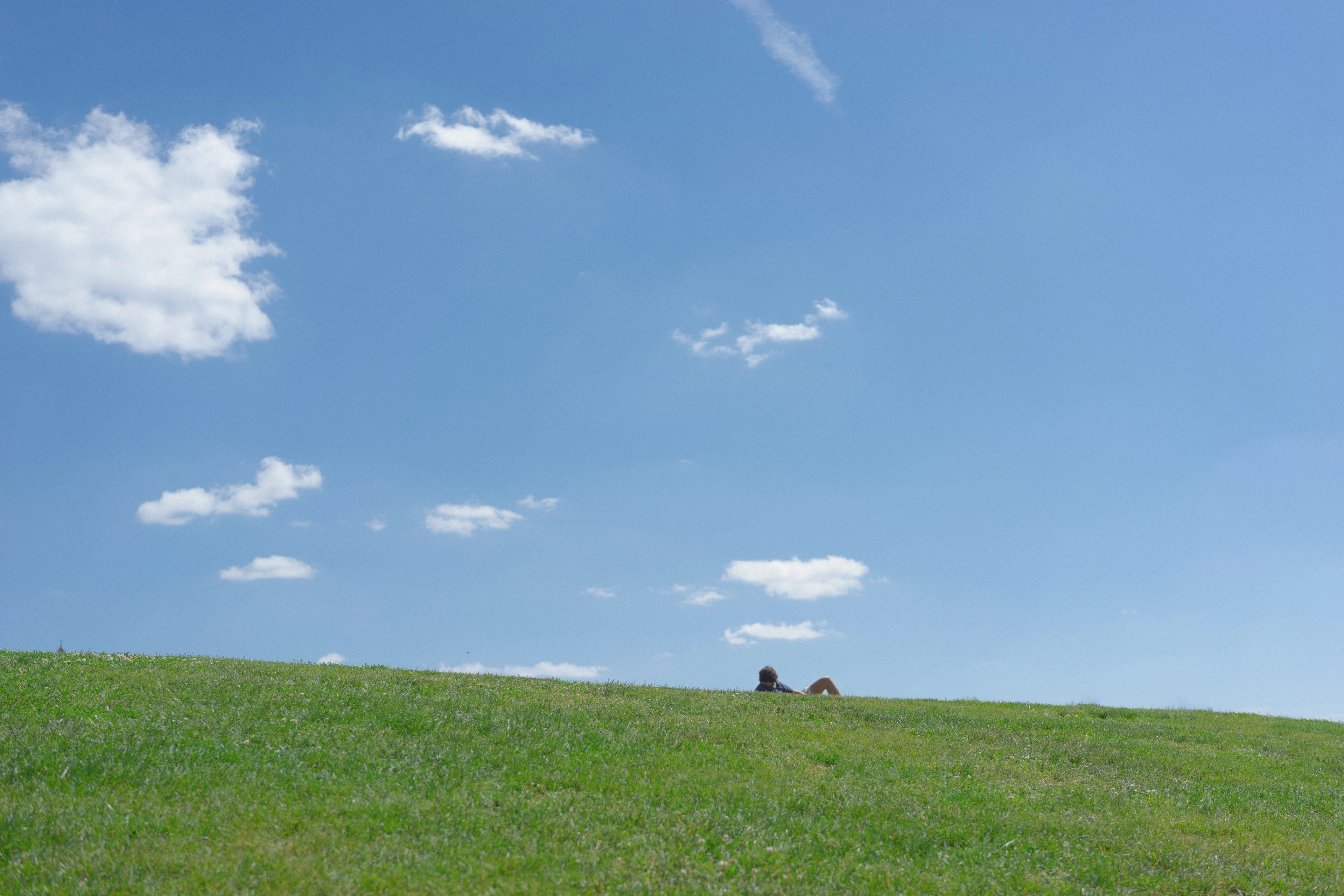 A wide expanse of blue sky scattered with soft clouds above a low hilltop, Washington, D.C.