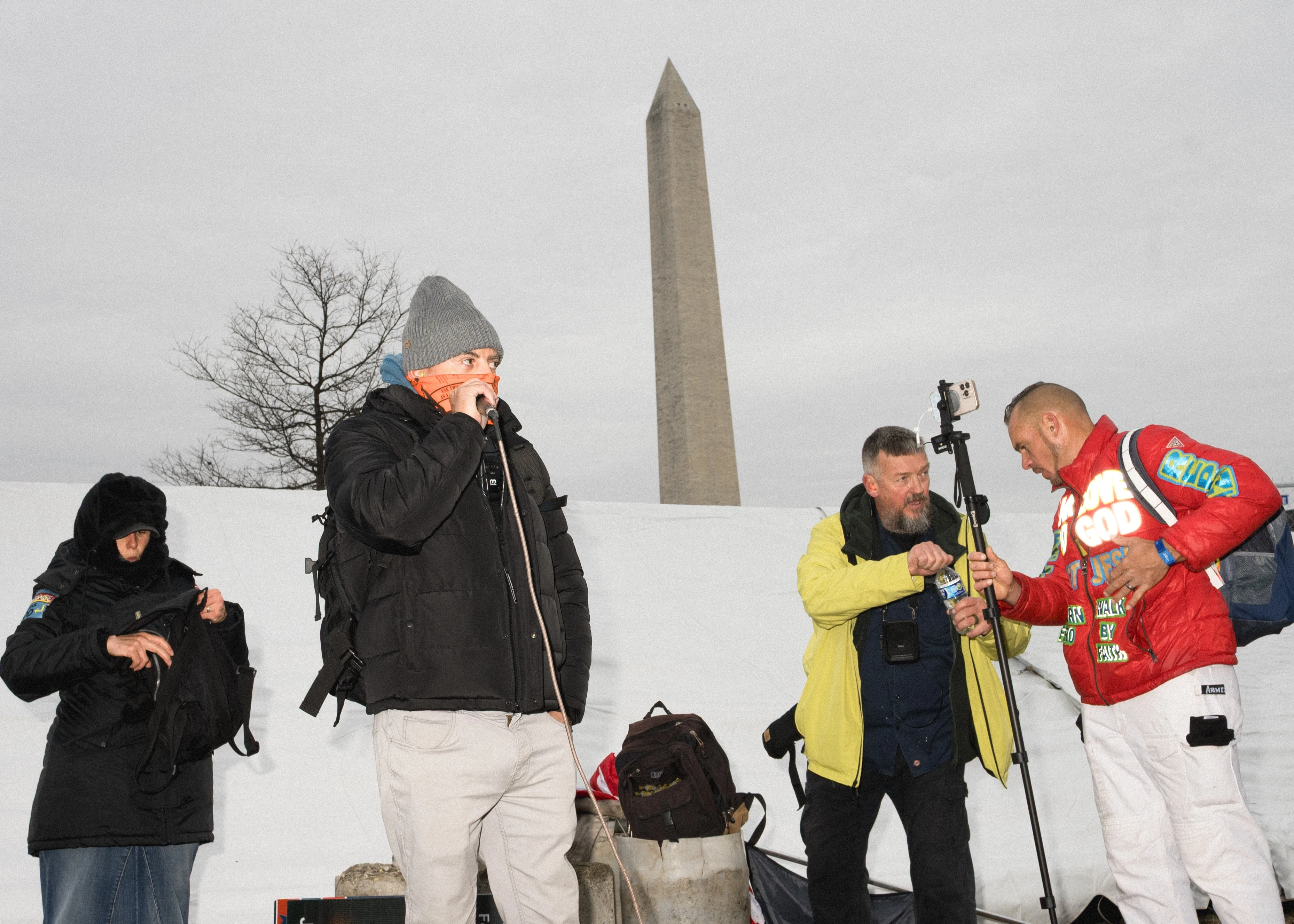 A small group stands on a low platform on the snow-covered National Mall in winter, Washington, D.C.